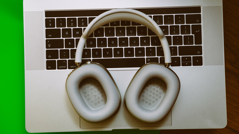 Apple AirPods Max resting neatly on a desk above a closed laptop.