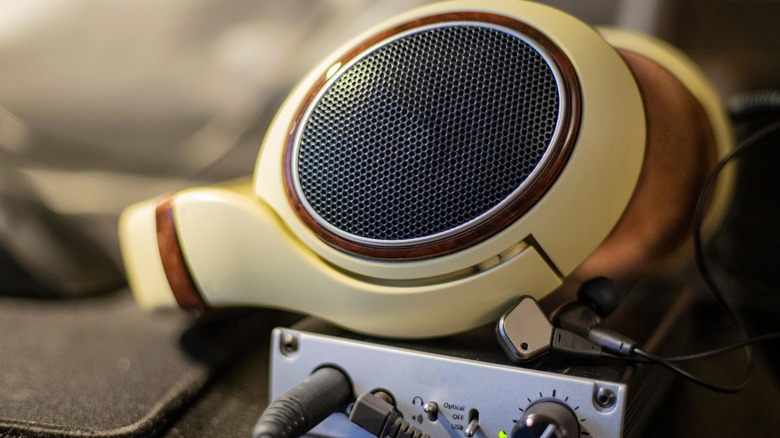Close-up of audiophile headphones connected to a high-end DAC and amplifier setup.