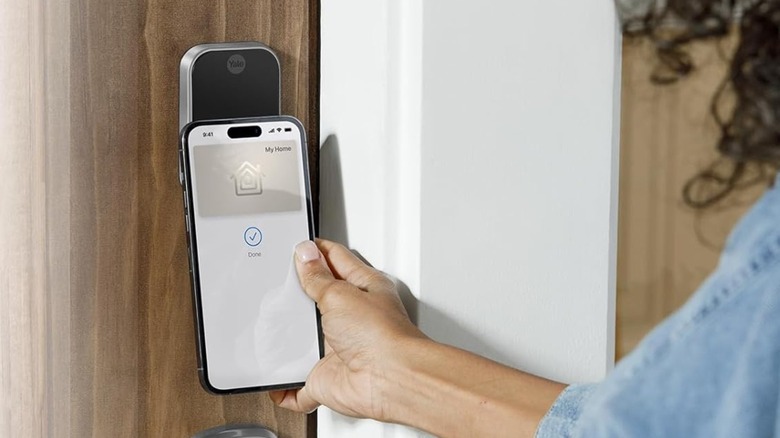A person unlocking a Yale smart lock by tapping their iPhone against it.