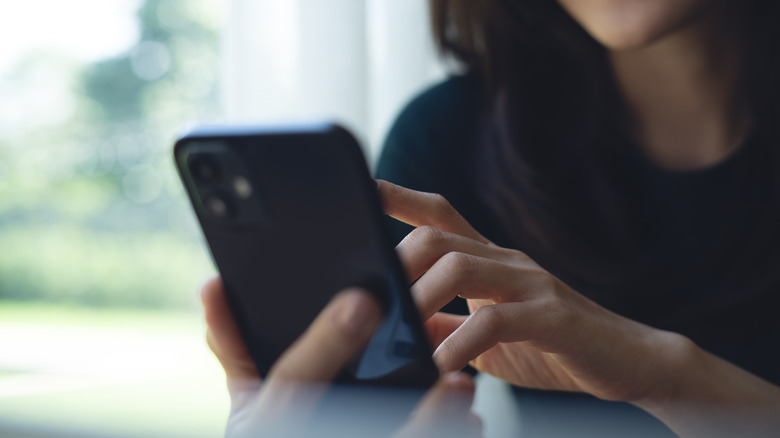 A woman using a smartphone to access the internal settings menu.
