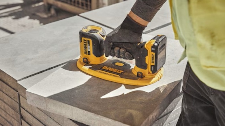 A person using the DeWalt Grabo lifter to pick up a large concrete block.