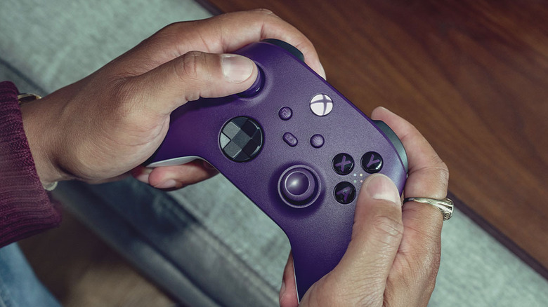 A person holding a purple Xbox wireless controller ready for pairing.