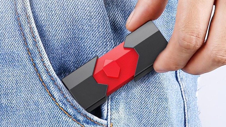 A close-up of a hand placing a dual-interface USB-A and USB-C flash drive into a pocket.