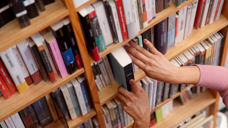 A person browsing books in a physical library or bookstore setting.