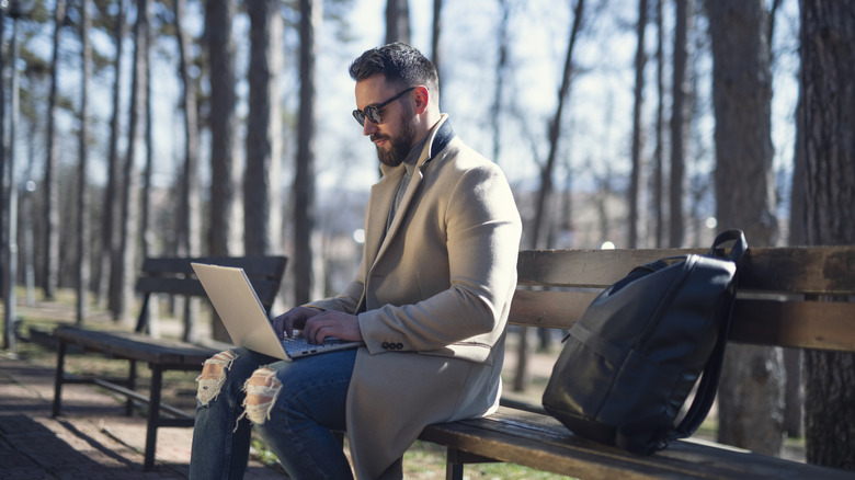 A professional working on a laptop while sitting on a bench, representing mobile workstation utility.