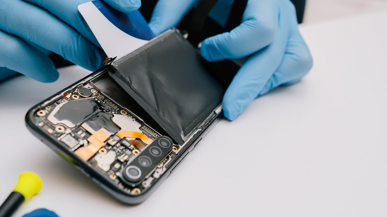 A technician performing a battery replacement on an Android device.