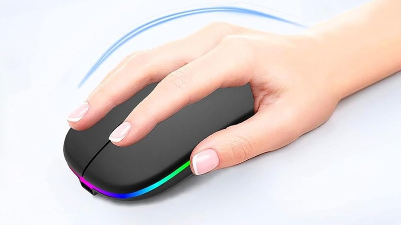 A hand resting on a black ergonomic wireless mouse with a rainbow LED strip.