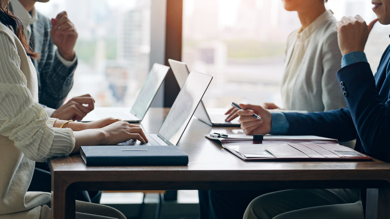 A group of young professionals using sleek modern laptops in a bright, contemporary office.
