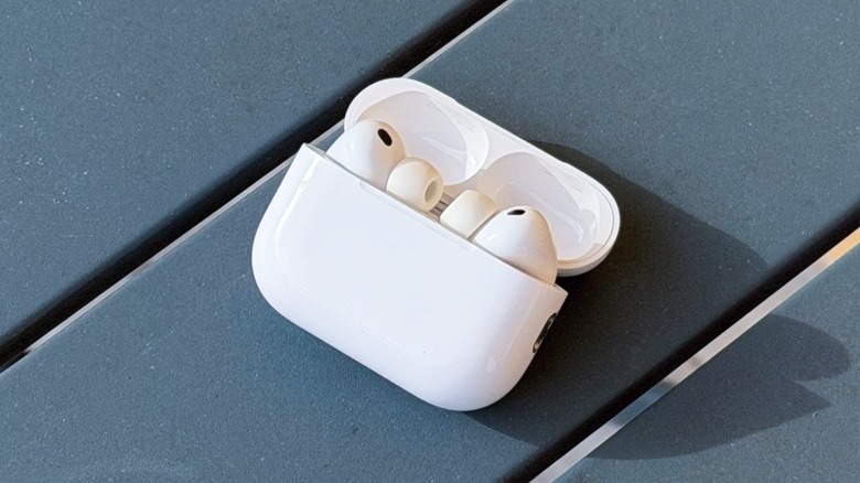 A pair of Apple AirPods Pro 3 resting on a wooden surface.