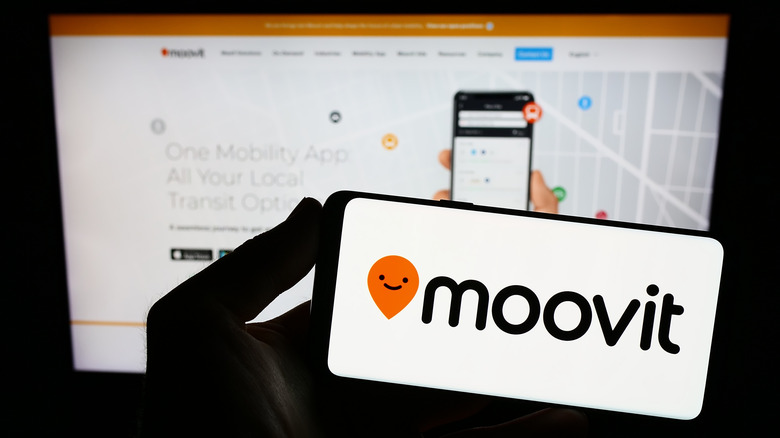 An iPhone screen displaying the Moovit logo in a dark environment.