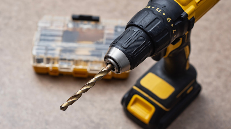 Close-up view of a metal drill bit inserted into the jaws of a keyless chuck.