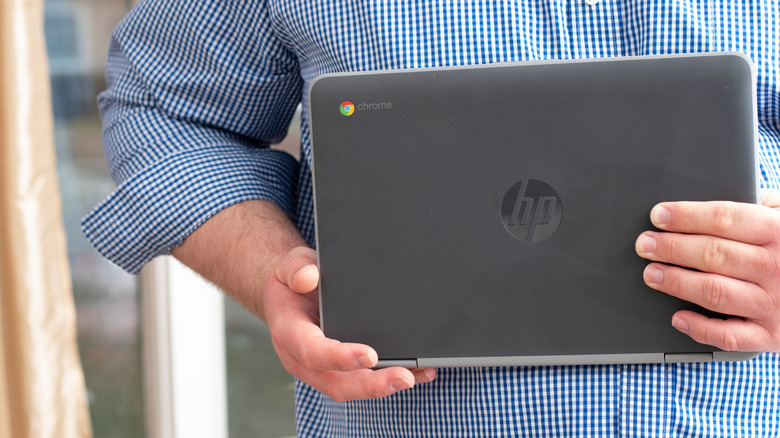 A person holding an HP Chromebook, showing its thin profile.