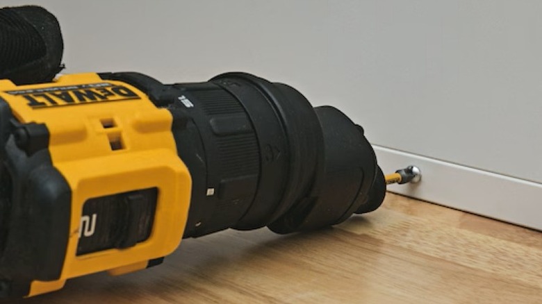 The DeWalt Atomic multi-head driver being used with an offset head to drive a screw in a narrow corner.