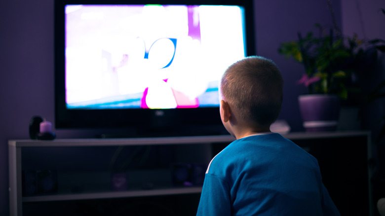 A small child looking at a bright television screen.