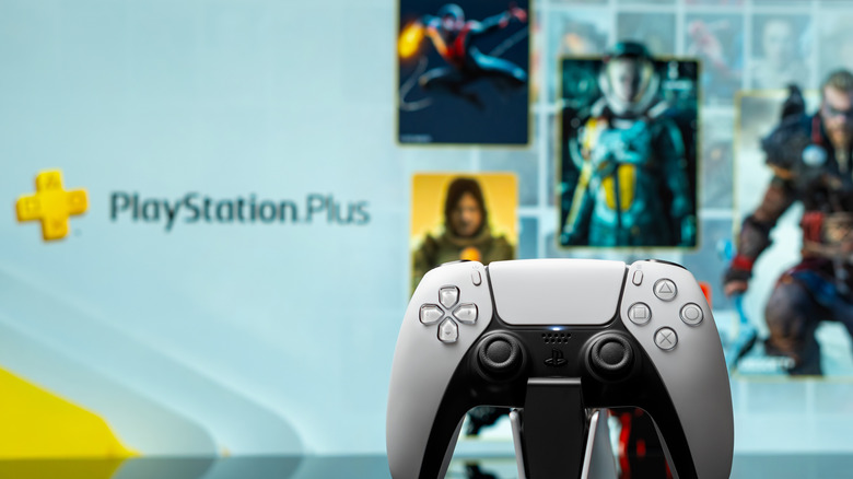 A close-up of a PS5 controller with various game cover tiles from the PS Plus Game Catalog.