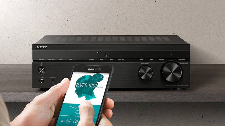 A person using a smartphone to wirelessly control a Sony AV receiver.