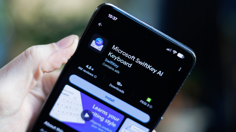 A hand holding a smartphone showing the Microsoft SwiftKey listing in the Play Store.