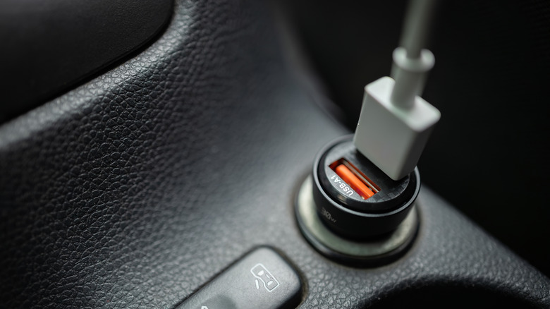 A USB car charger plugged into a vehicle's 12V cigarette lighter socket for on-the-go drone battery charging.